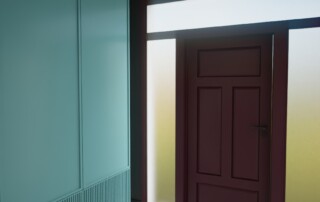 Odważne wnętrze z kolorem – hol z zieloną zabudową, bordowymi drzwiami i geometryczną posadzką.